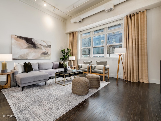 living room with rail lighting, ornamental molding, and dark wood-type flooring