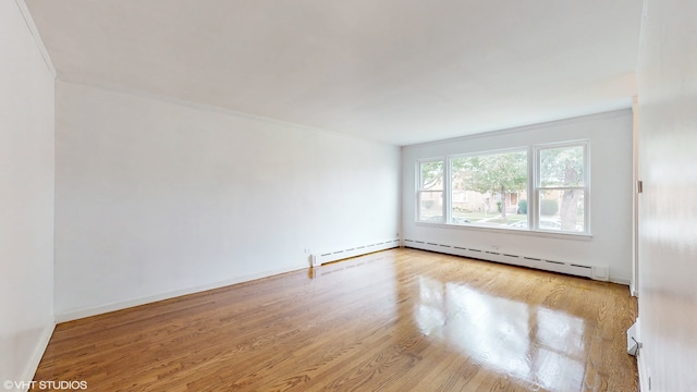 spare room with light hardwood / wood-style flooring, a baseboard heating unit, and crown molding