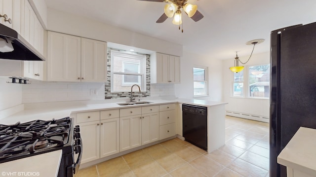 kitchen featuring decorative light fixtures, a wealth of natural light, sink, and black appliances