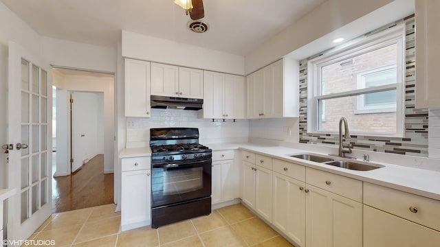 kitchen featuring black gas stove, backsplash, light tile patterned floors, and sink