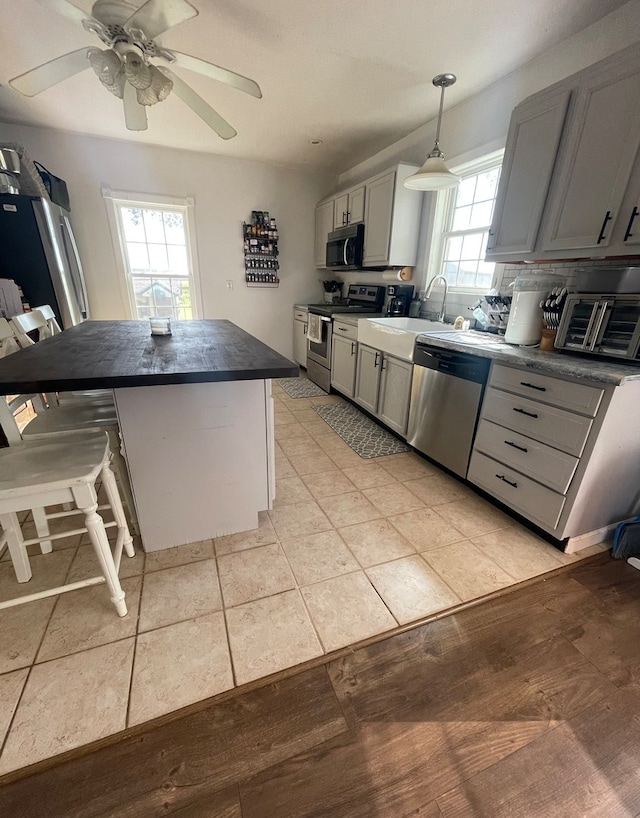 kitchen with gray cabinets, stainless steel appliances, ceiling fan, and a wealth of natural light