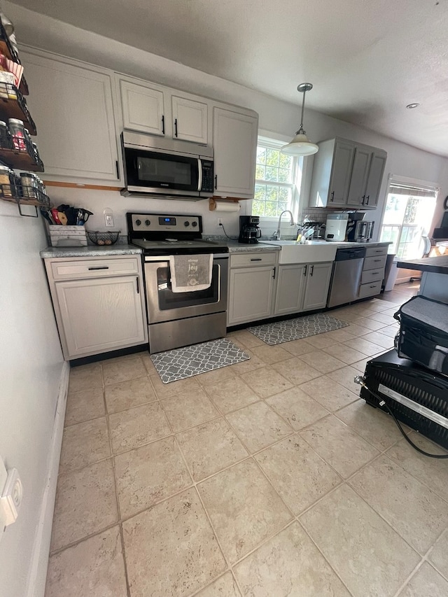 kitchen with pendant lighting, a wealth of natural light, appliances with stainless steel finishes, and gray cabinets