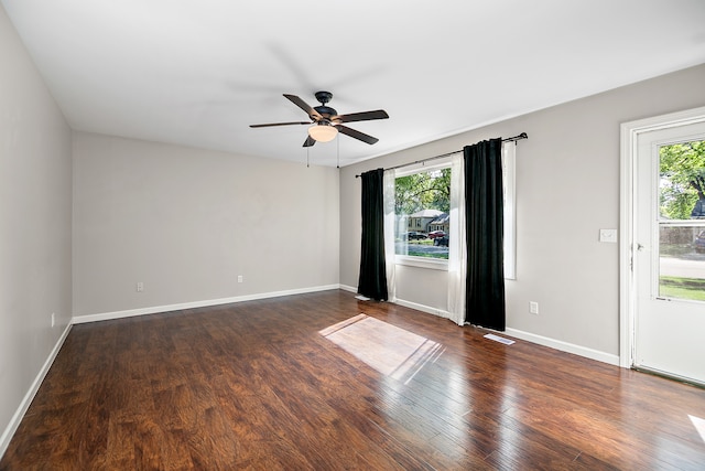 empty room with ceiling fan, dark hardwood / wood-style flooring, and a wealth of natural light