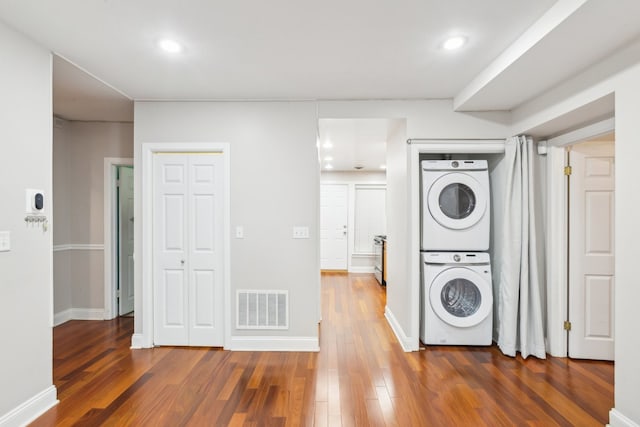 laundry room featuring dark wood-type flooring and stacked washer / drying machine