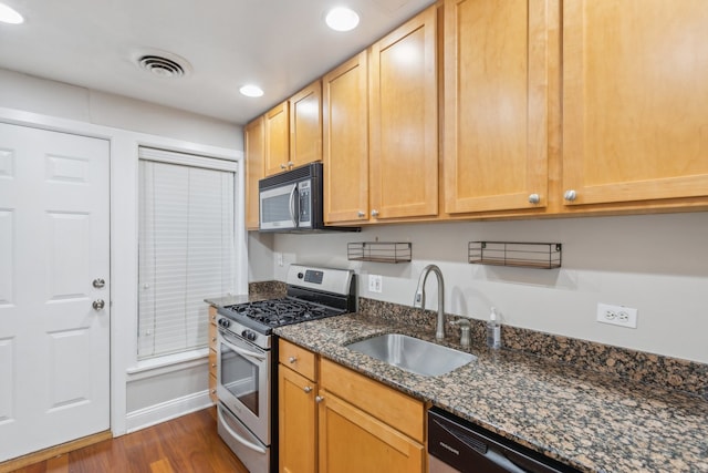 kitchen with dark stone countertops, stainless steel appliances, dark wood-type flooring, and sink