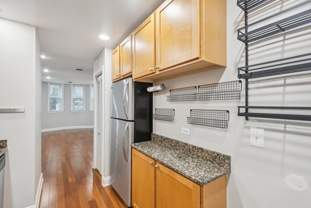 kitchen featuring stainless steel refrigerator, dark stone counters, and dark hardwood / wood-style flooring