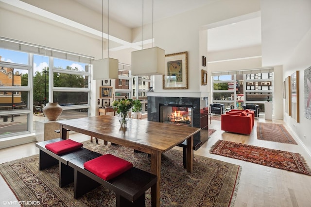 dining space featuring hardwood / wood-style floors, a high end fireplace, plenty of natural light, and a high ceiling