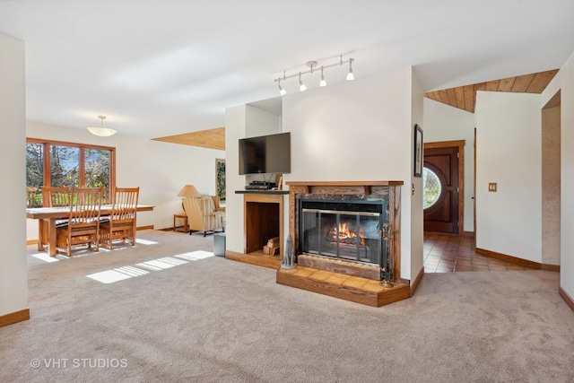 carpeted living room with a tiled fireplace, rail lighting, and vaulted ceiling