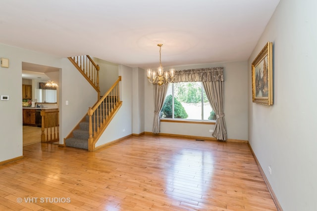 empty room with a chandelier and light hardwood / wood-style floors