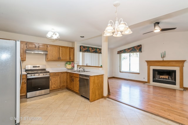 kitchen with light wood-type flooring, ceiling fan with notable chandelier, vaulted ceiling, hanging light fixtures, and appliances with stainless steel finishes