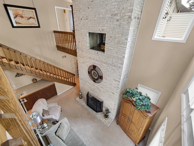 carpeted living room featuring a high ceiling and a fireplace