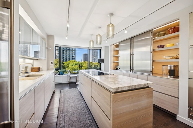 kitchen featuring sink, decorative light fixtures, black electric cooktop, dark hardwood / wood-style floors, and a kitchen island