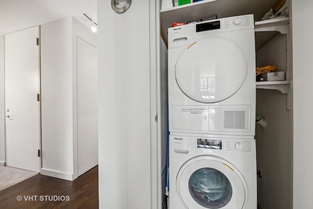 laundry area with dark wood-type flooring and stacked washer / drying machine