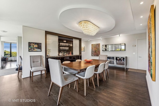 dining area featuring an inviting chandelier, dark wood-type flooring, and bar