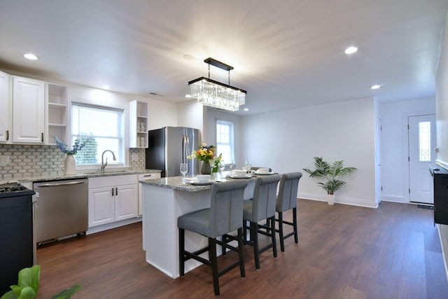 kitchen featuring white cabinetry, stainless steel appliances, a center island, and pendant lighting