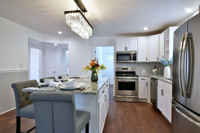 kitchen featuring appliances with stainless steel finishes, a center island, a breakfast bar area, and white cabinets