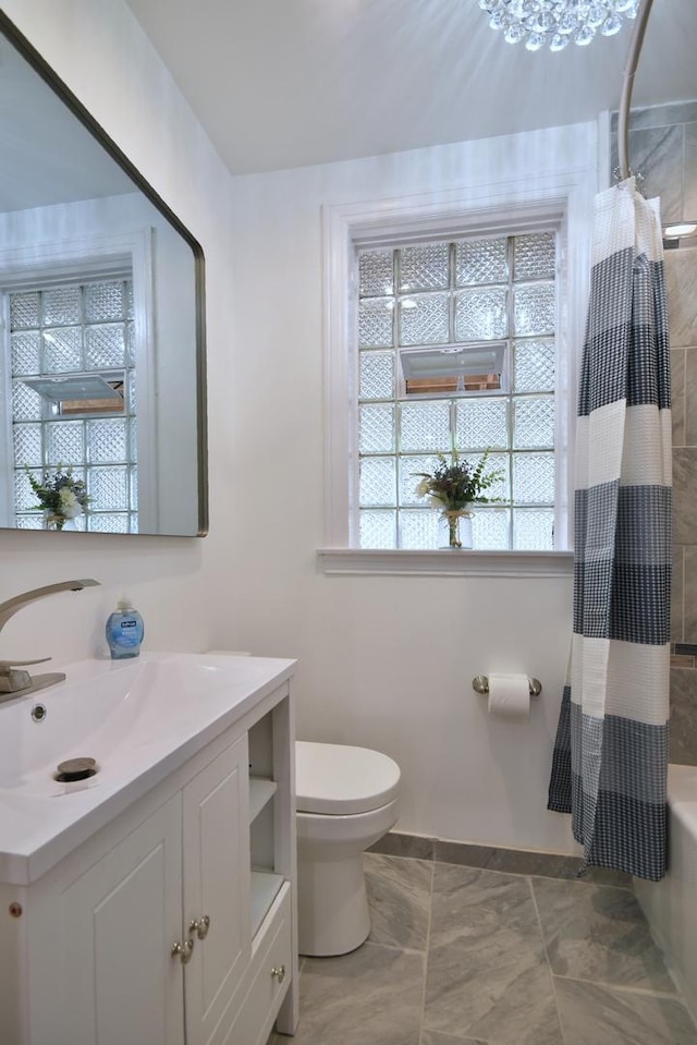 full bathroom featuring vanity, a chandelier, shower / bath combo with shower curtain, and toilet