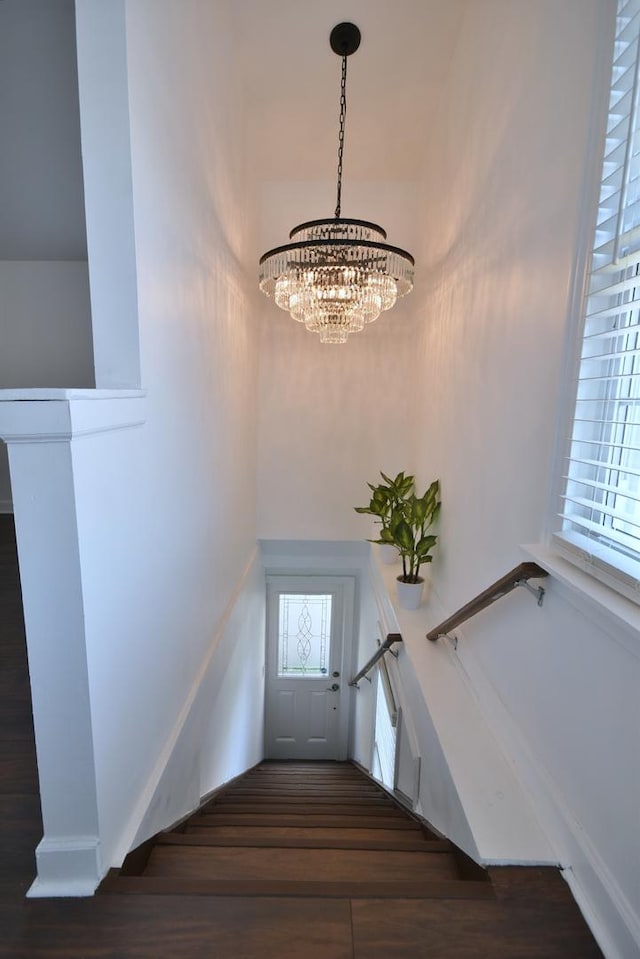 stairway featuring hardwood / wood-style floors and an inviting chandelier