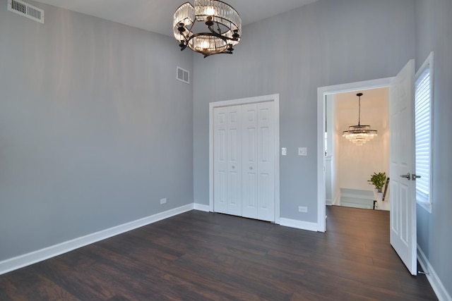 unfurnished bedroom featuring dark wood-type flooring, a closet, and a chandelier