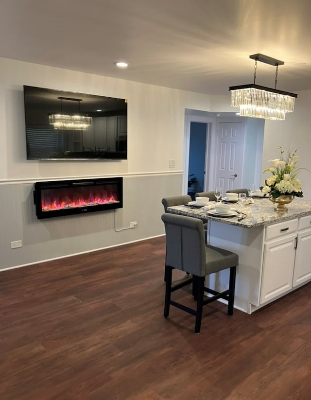 kitchen featuring pendant lighting, dark hardwood / wood-style floors, a breakfast bar area, and white cabinets