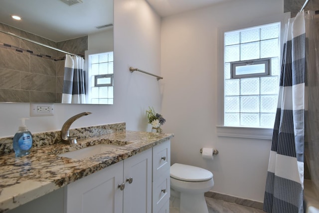 bathroom featuring vanity, a wealth of natural light, and toilet