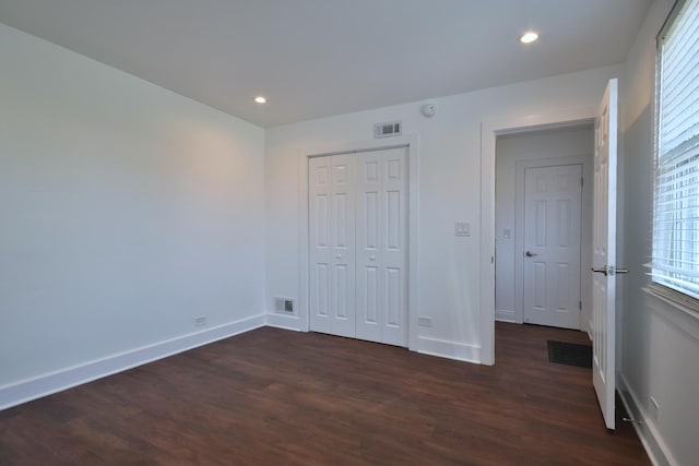 unfurnished bedroom with dark wood-type flooring and a closet