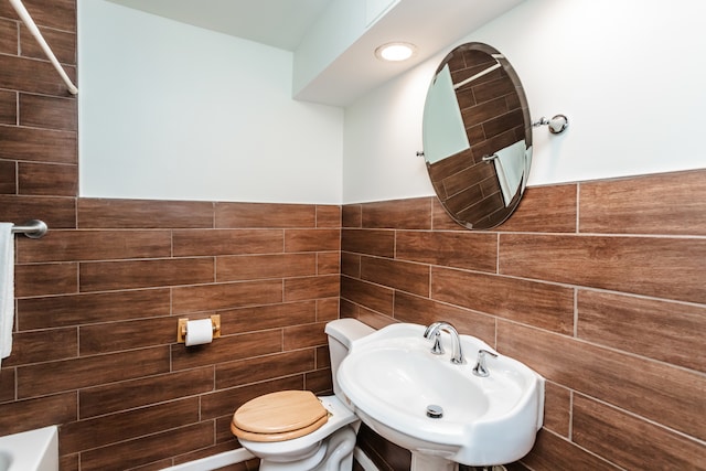 bathroom with tile walls, sink, and toilet