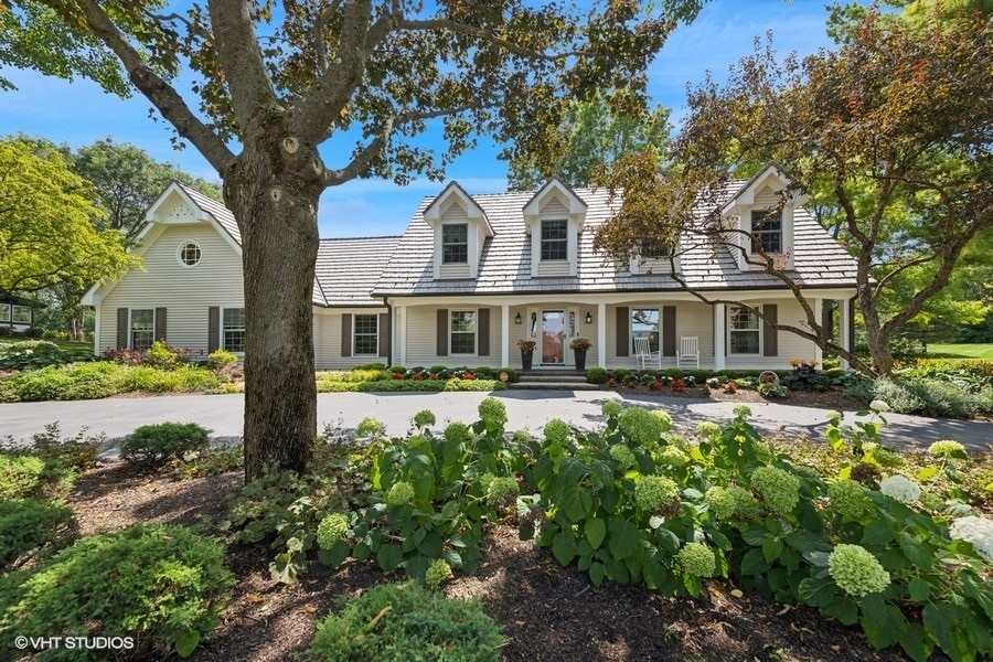 cape cod home featuring a balcony and covered porch