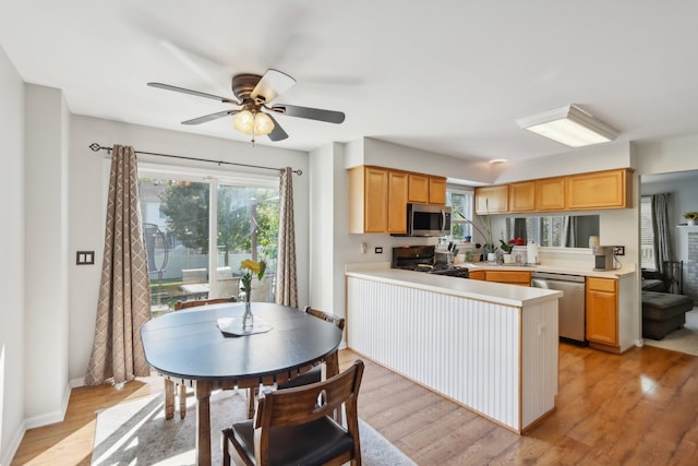 kitchen featuring kitchen peninsula, stainless steel appliances, light wood-type flooring, light brown cabinetry, and ceiling fan