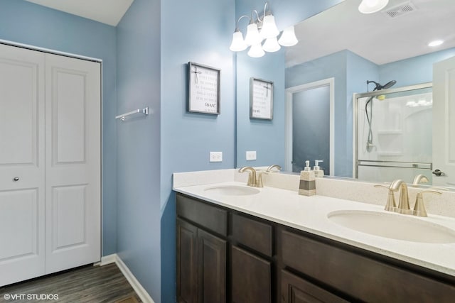 bathroom featuring wood-type flooring, vanity, walk in shower, and a notable chandelier