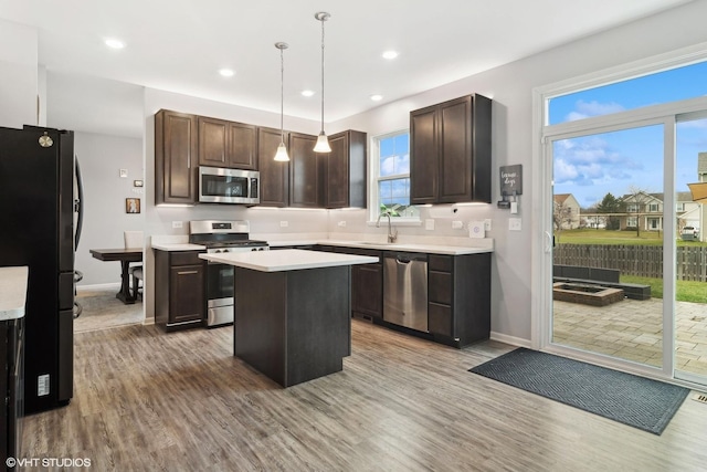 kitchen with plenty of natural light, a center island, stainless steel appliances, and decorative light fixtures