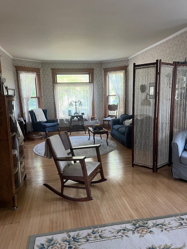 living room with ornamental molding, light wood-type flooring, and a healthy amount of sunlight