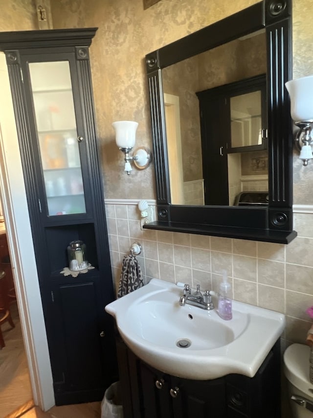 bathroom with vanity, toilet, decorative backsplash, and tile walls