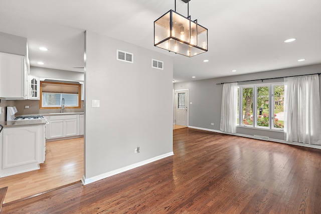 interior space featuring wood-type flooring, white cabinetry, sink, and decorative light fixtures