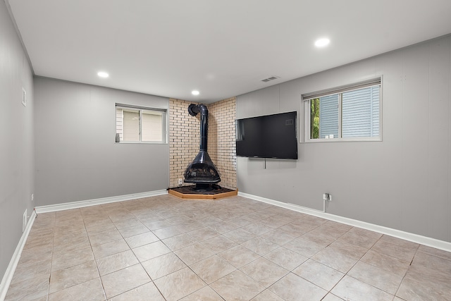 unfurnished living room featuring light tile patterned flooring and a wood stove