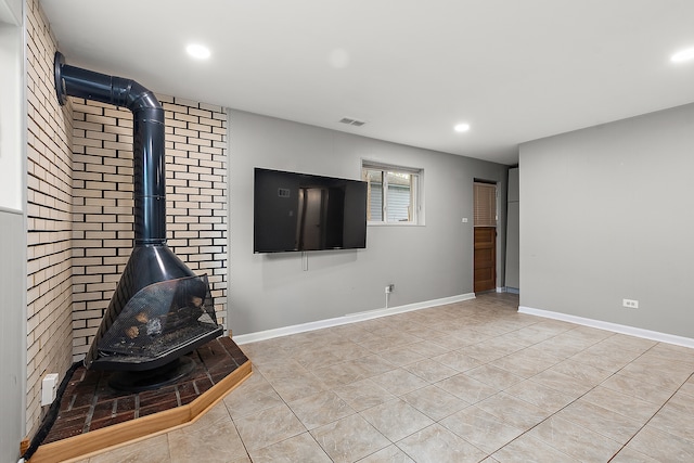 unfurnished living room with brick wall, light tile patterned floors, and a wood stove