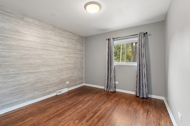 unfurnished room featuring wood walls and dark wood-type flooring