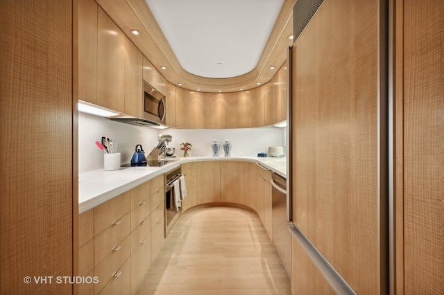 kitchen with light brown cabinets, appliances with stainless steel finishes, and light hardwood / wood-style floors