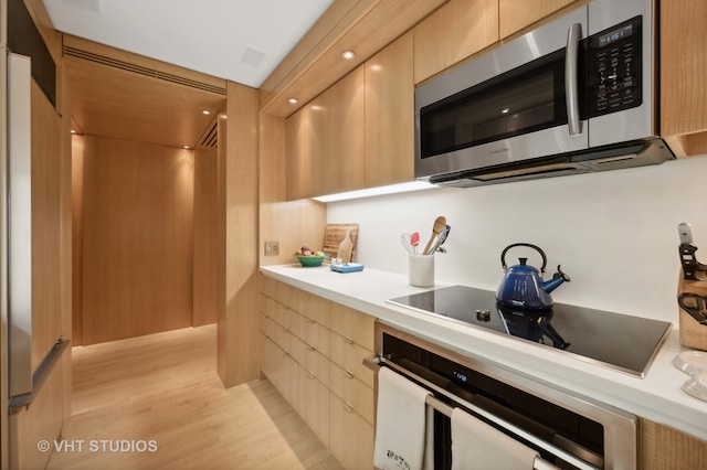 kitchen with appliances with stainless steel finishes, light brown cabinetry, and light hardwood / wood-style flooring