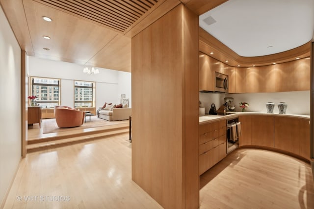 kitchen featuring light wood-type flooring, a chandelier, and stainless steel appliances