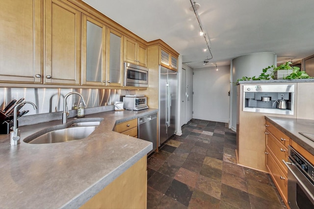 kitchen with decorative backsplash, track lighting, built in appliances, and sink