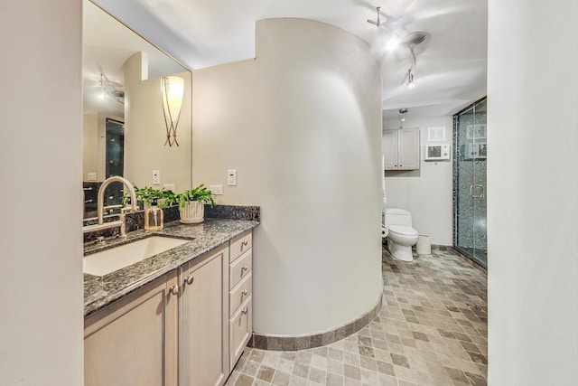 bathroom featuring a shower with shower door, vanity, and toilet