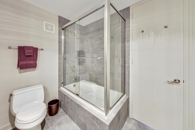 bathroom with bath / shower combo with glass door, tile patterned floors, and toilet