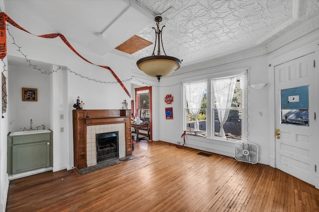 living room featuring wood-type flooring, sink, and a tile fireplace