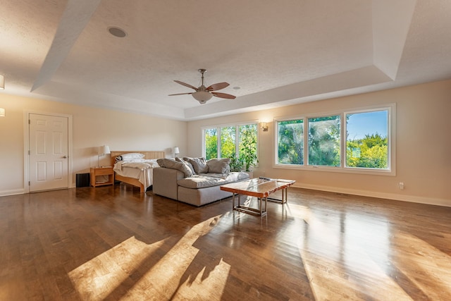 bedroom featuring ceiling fan, a tray ceiling, and dark hardwood / wood-style floors