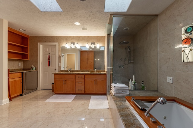 bathroom featuring vanity, a skylight, a textured ceiling, plus walk in shower, and tile patterned floors