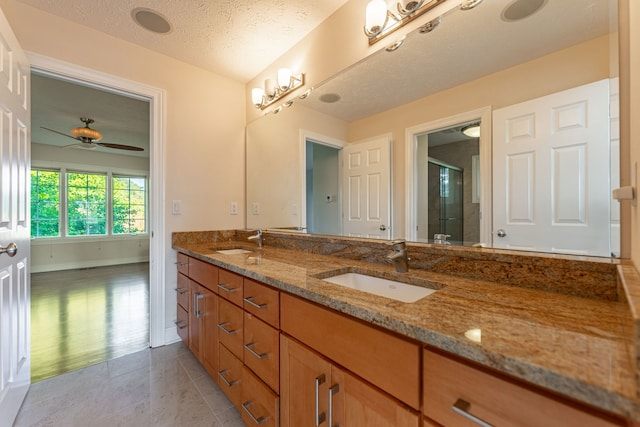 bathroom with ceiling fan, vanity, a textured ceiling, tile patterned floors, and walk in shower