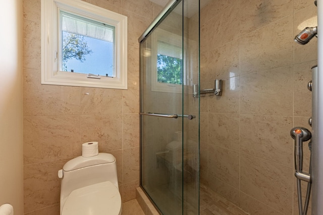 bathroom with a shower with shower door, toilet, and plenty of natural light