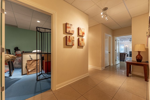 hallway featuring a drop ceiling and tile patterned flooring