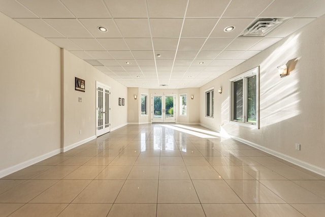 tiled spare room featuring a paneled ceiling and french doors